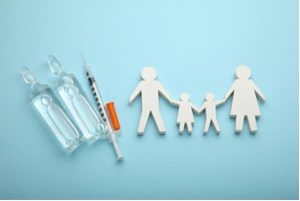Paper family holding hands next to a vaccination syringe.